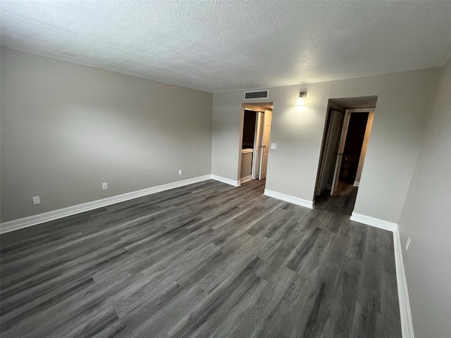 empty room featuring a textured ceiling and dark wood-type flooring