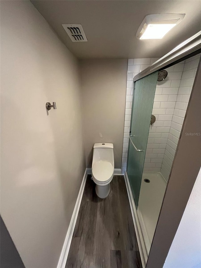 bathroom with hardwood / wood-style flooring, toilet, and a shower with door