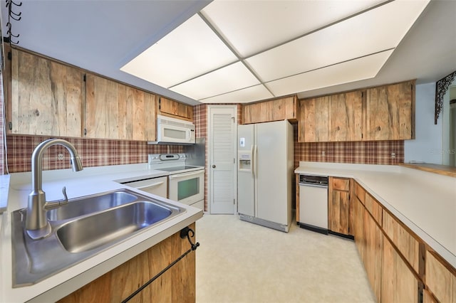 kitchen featuring backsplash, sink, a drop ceiling, and white appliances