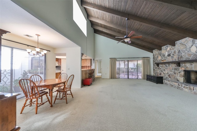 carpeted dining room with wooden ceiling, a stone fireplace, beamed ceiling, high vaulted ceiling, and ceiling fan with notable chandelier