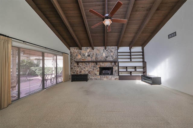 unfurnished living room with carpet flooring, beam ceiling, ceiling fan, a stone fireplace, and wood ceiling