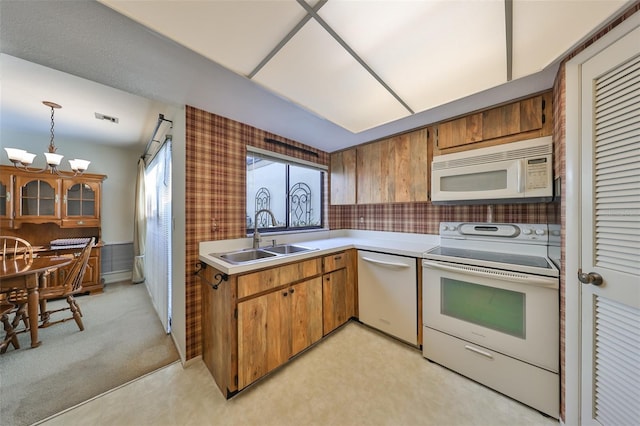 kitchen featuring white appliances, light colored carpet, sink, pendant lighting, and a chandelier