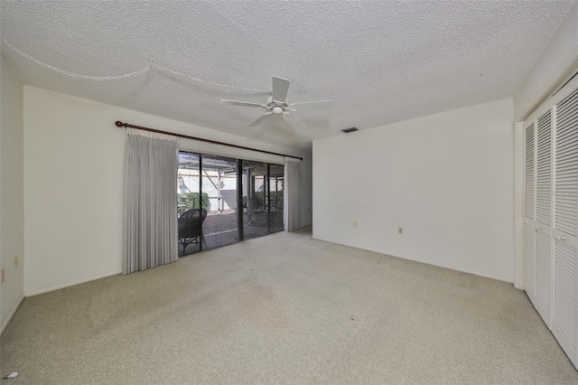 carpeted empty room featuring ceiling fan and a textured ceiling