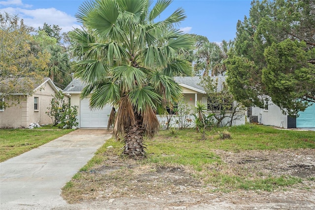 view of property hidden behind natural elements featuring a garage and concrete driveway