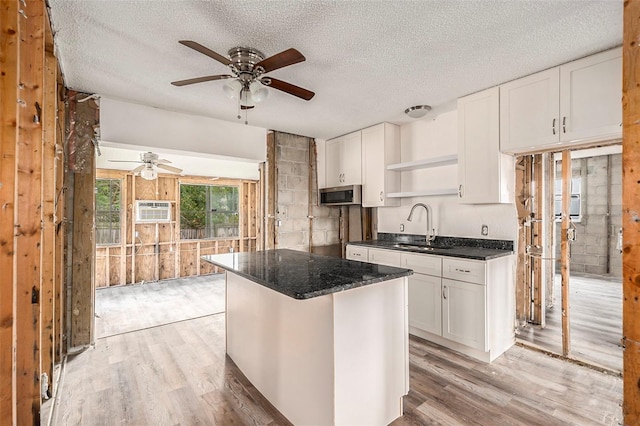 kitchen featuring a textured ceiling, a kitchen island, sink, light hardwood / wood-style floors, and white cabinetry