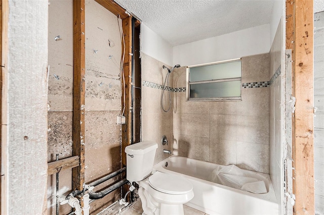 bathroom featuring a textured ceiling, toilet, and tiled shower / bath combo