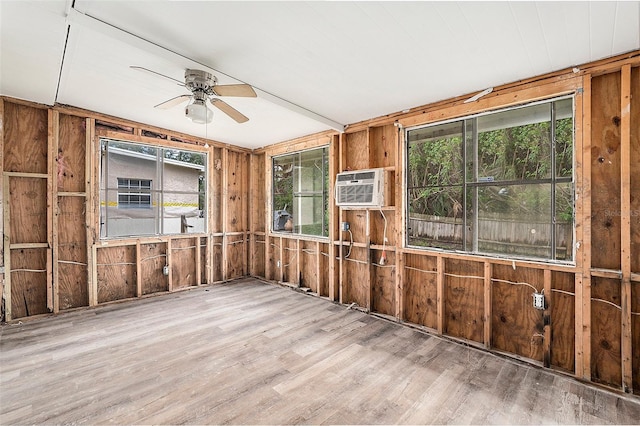 interior space featuring a wall mounted air conditioner, light hardwood / wood-style flooring, ceiling fan, and wooden walls