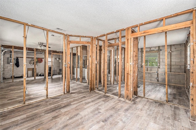 basement featuring hardwood / wood-style floors, ceiling fan, and a textured ceiling