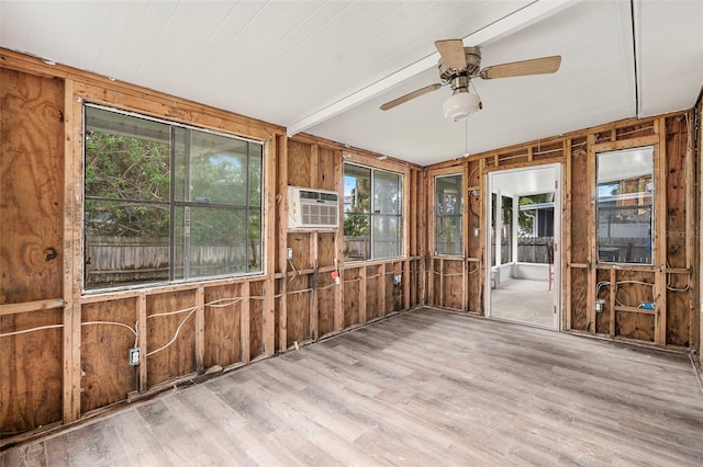 unfurnished sunroom featuring a wall unit AC, ceiling fan, and beam ceiling