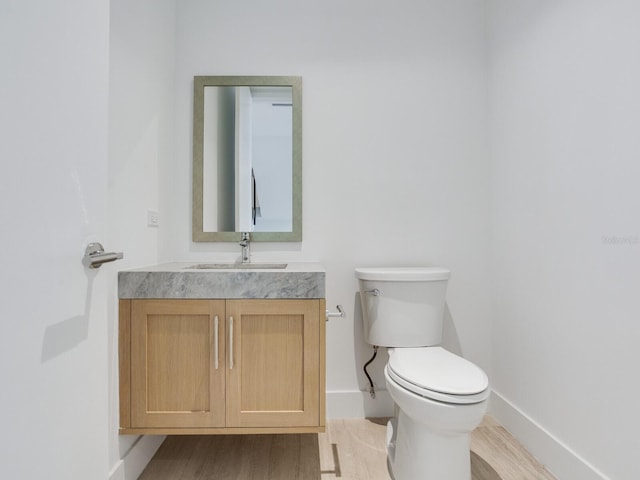 bathroom featuring toilet, vanity, and hardwood / wood-style flooring