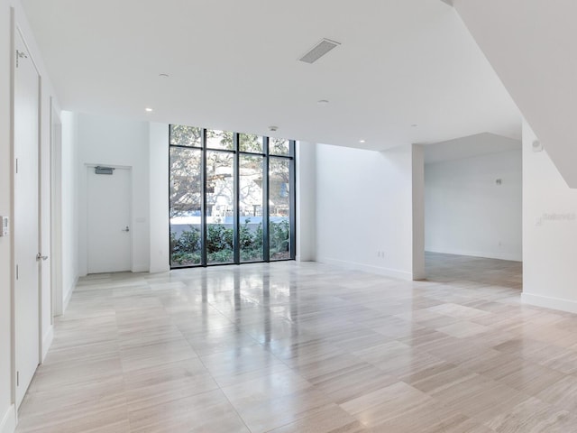 tiled empty room featuring floor to ceiling windows