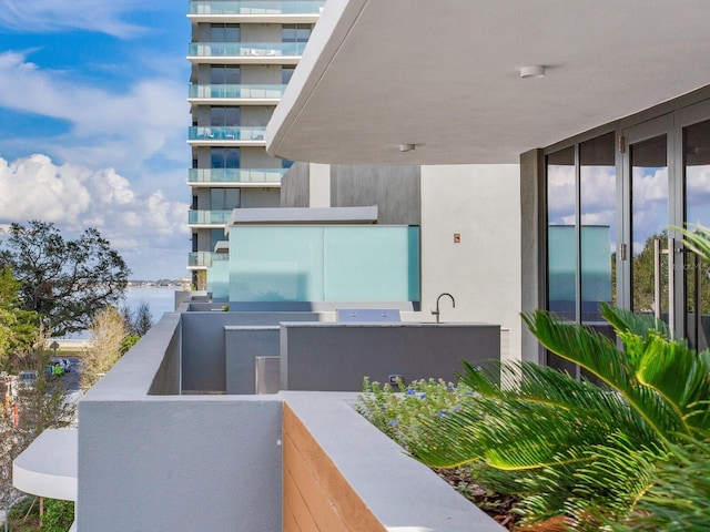 view of patio / terrace featuring a balcony, a water view, and sink