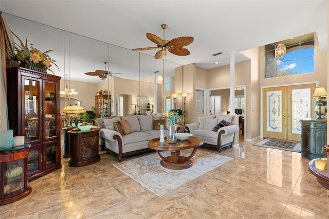 living room featuring a notable chandelier, decorative columns, a high ceiling, and french doors