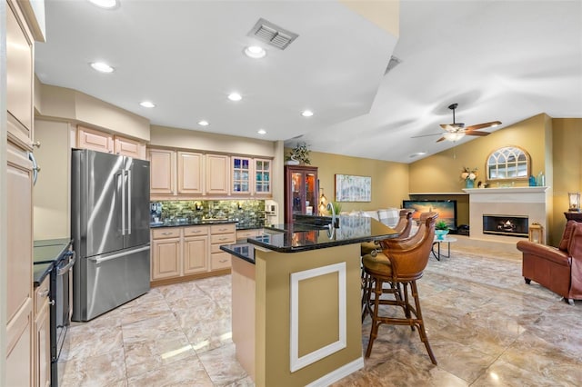 kitchen featuring ceiling fan, black range with electric cooktop, backsplash, stainless steel fridge, and a breakfast bar area