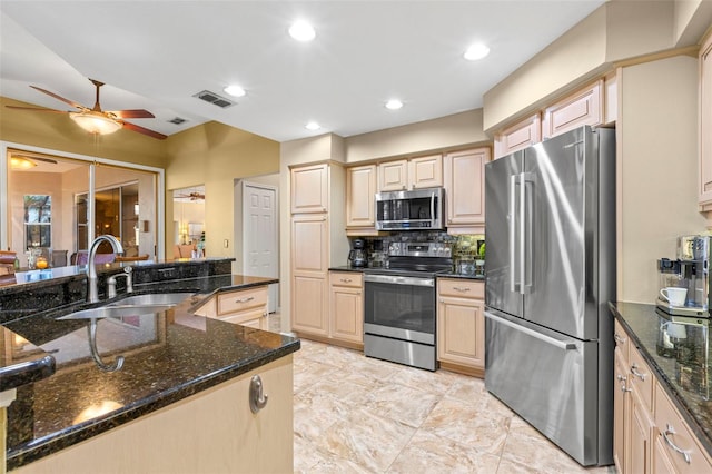 kitchen with dark stone countertops, ceiling fan, sink, and stainless steel appliances