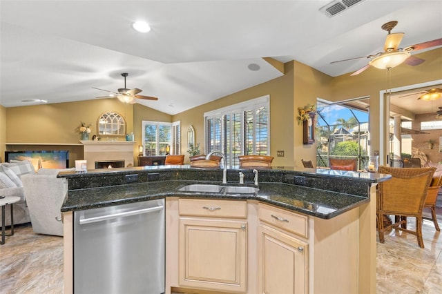 kitchen featuring a kitchen island with sink, sink, vaulted ceiling, stainless steel dishwasher, and dark stone countertops