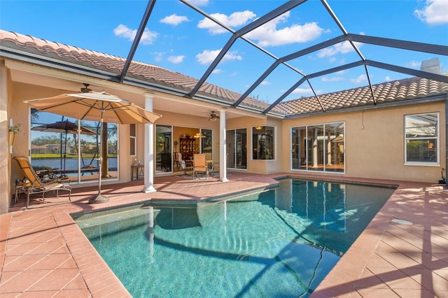 view of swimming pool with a lanai, a patio area, ceiling fan, and a water view