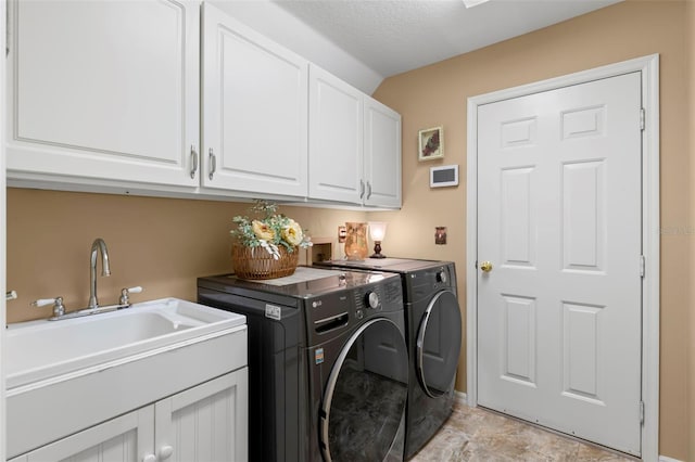 laundry area with washing machine and dryer, sink, cabinets, and a textured ceiling