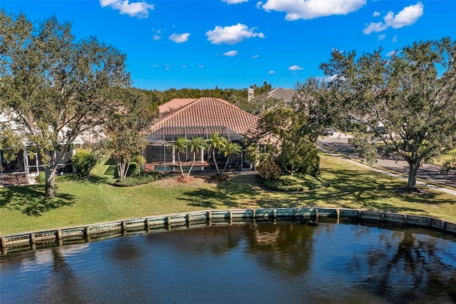 exterior space featuring a water view, a lanai, and a lawn