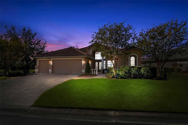 mediterranean / spanish house featuring a lawn and a garage