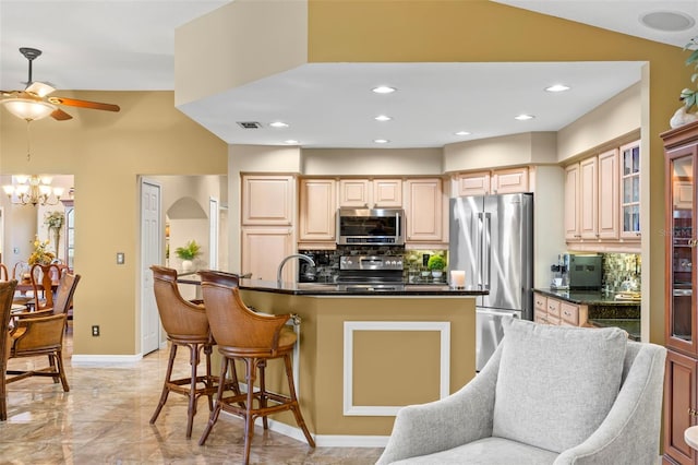 kitchen with light brown cabinetry, ceiling fan with notable chandelier, tasteful backsplash, and stainless steel appliances