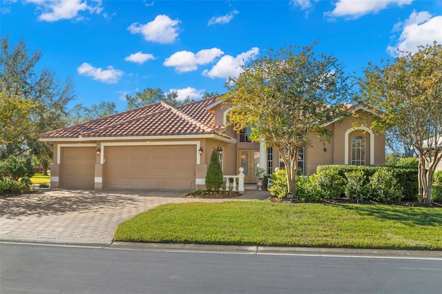 mediterranean / spanish house featuring a garage and a front lawn