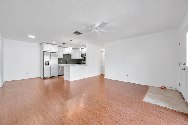 unfurnished living room featuring light wood-type flooring, sink, and ceiling fan