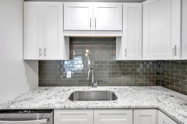 kitchen featuring white cabinets, sink, stainless steel dishwasher, and backsplash