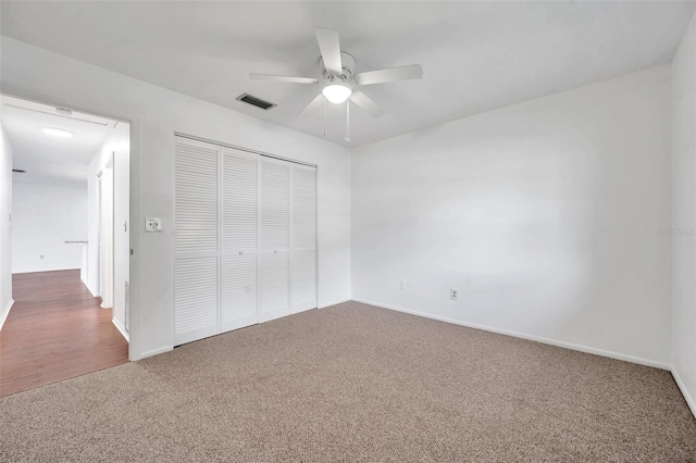 unfurnished bedroom with ceiling fan, a closet, and dark colored carpet