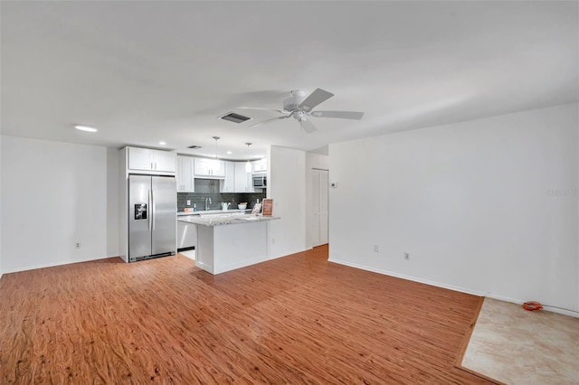 kitchen featuring white cabinetry, tasteful backsplash, kitchen peninsula, pendant lighting, and stainless steel appliances