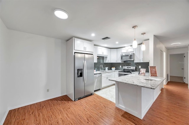 kitchen featuring white cabinetry, sink, kitchen peninsula, stainless steel appliances, and light stone countertops