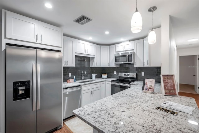 kitchen with sink, white cabinetry, pendant lighting, stainless steel appliances, and decorative backsplash