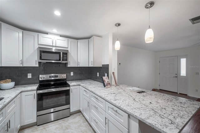 kitchen with pendant lighting, tasteful backsplash, white cabinets, kitchen peninsula, and stainless steel appliances