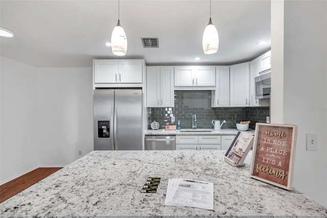 kitchen with stainless steel appliances, sink, hanging light fixtures, and white cabinets