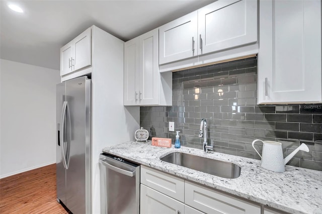 kitchen featuring sink, light hardwood / wood-style flooring, appliances with stainless steel finishes, light stone countertops, and white cabinets