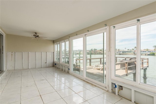 unfurnished sunroom featuring ceiling fan, plenty of natural light, and a water view