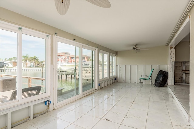 unfurnished sunroom with a water view and ceiling fan