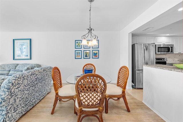 dining area with light hardwood / wood-style floors and a notable chandelier