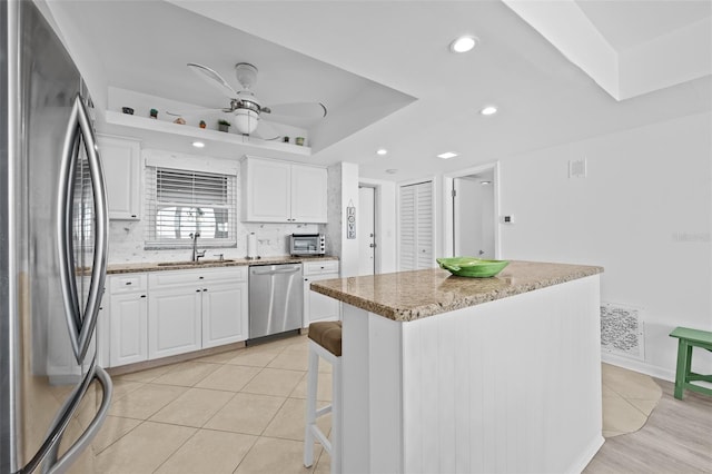 kitchen featuring white cabinets, a kitchen island, sink, and stainless steel appliances