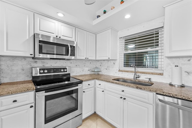 kitchen with decorative backsplash, appliances with stainless steel finishes, light stone countertops, sink, and white cabinets