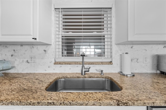 kitchen featuring backsplash, sink, and white cabinets