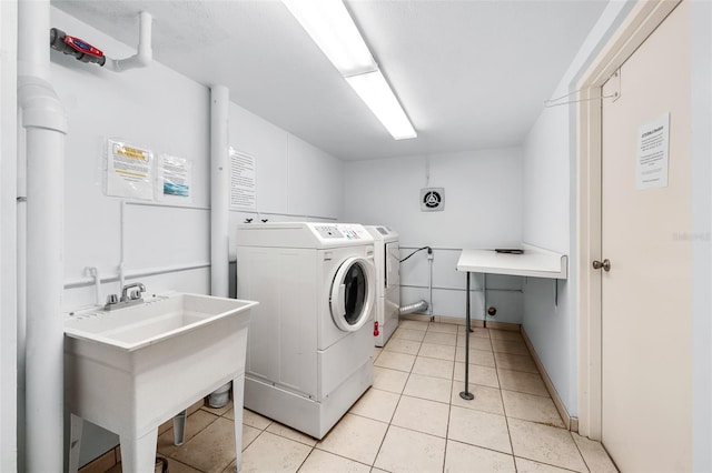 laundry area featuring washer and clothes dryer, sink, and light tile patterned flooring