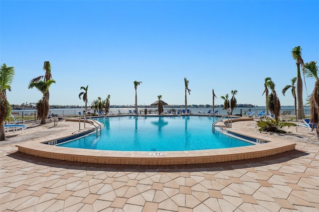 view of pool featuring a water view and a patio