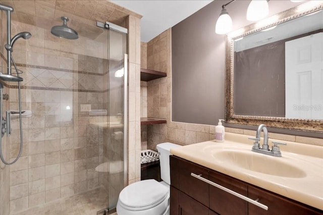 bathroom with vanity, toilet, a shower with door, and tile walls