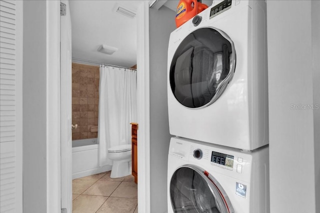 laundry area featuring stacked washer and dryer and light tile patterned floors