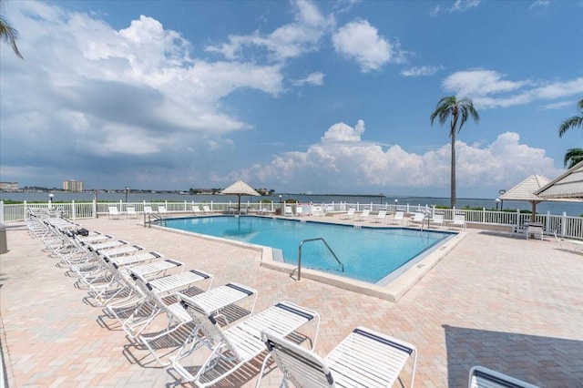 view of swimming pool featuring a patio and a water view