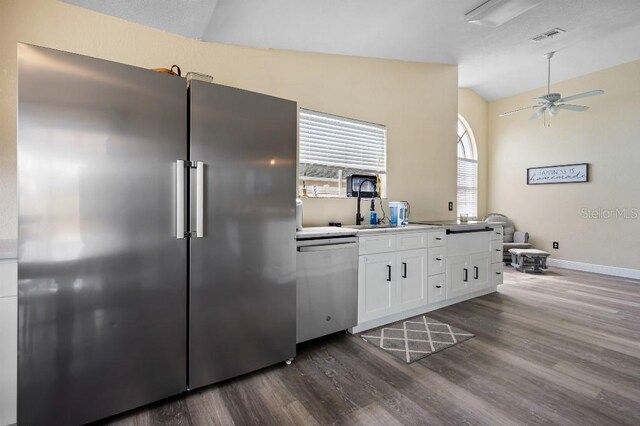 kitchen featuring white cabinets, dark hardwood / wood-style floors, stainless steel appliances, and vaulted ceiling