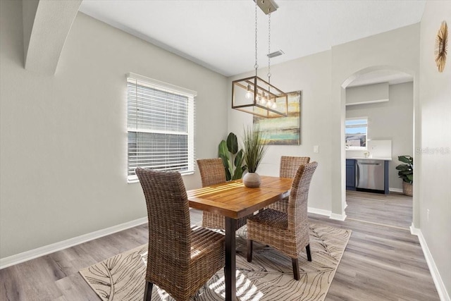 dining room with a healthy amount of sunlight, light hardwood / wood-style flooring, and a chandelier