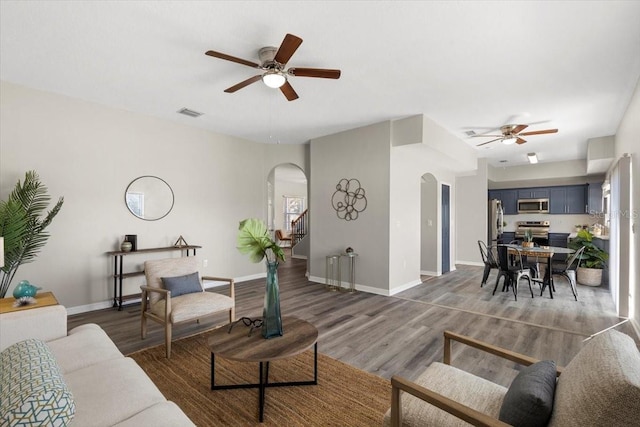 living room with ceiling fan and dark wood-type flooring