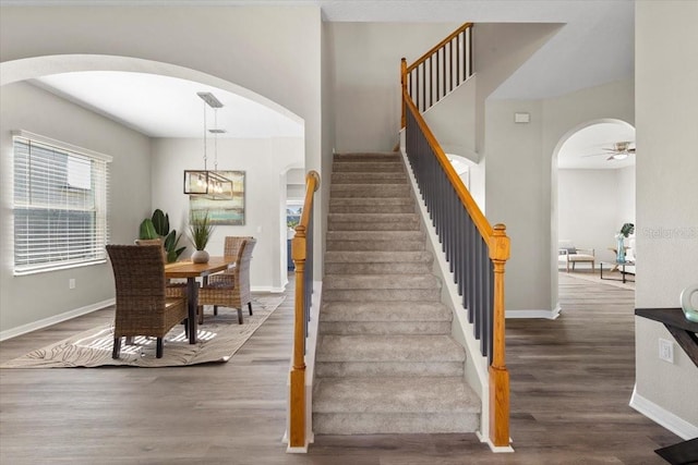 stairs with ceiling fan with notable chandelier and hardwood / wood-style flooring